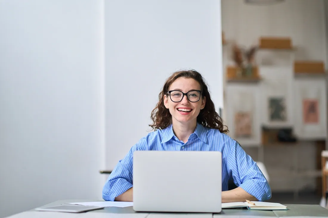 Femme avec des lunettes souriante utilisant son ordinateur portable 