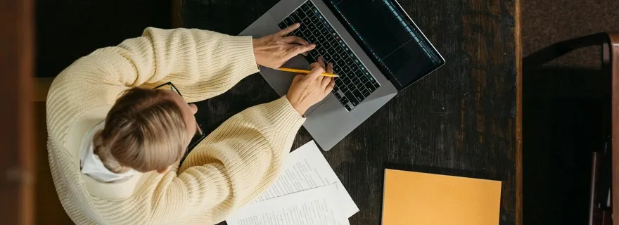 Personne travaillant sur un ordinateur portable avec des notes manuscrites, organisation et productivité au travail